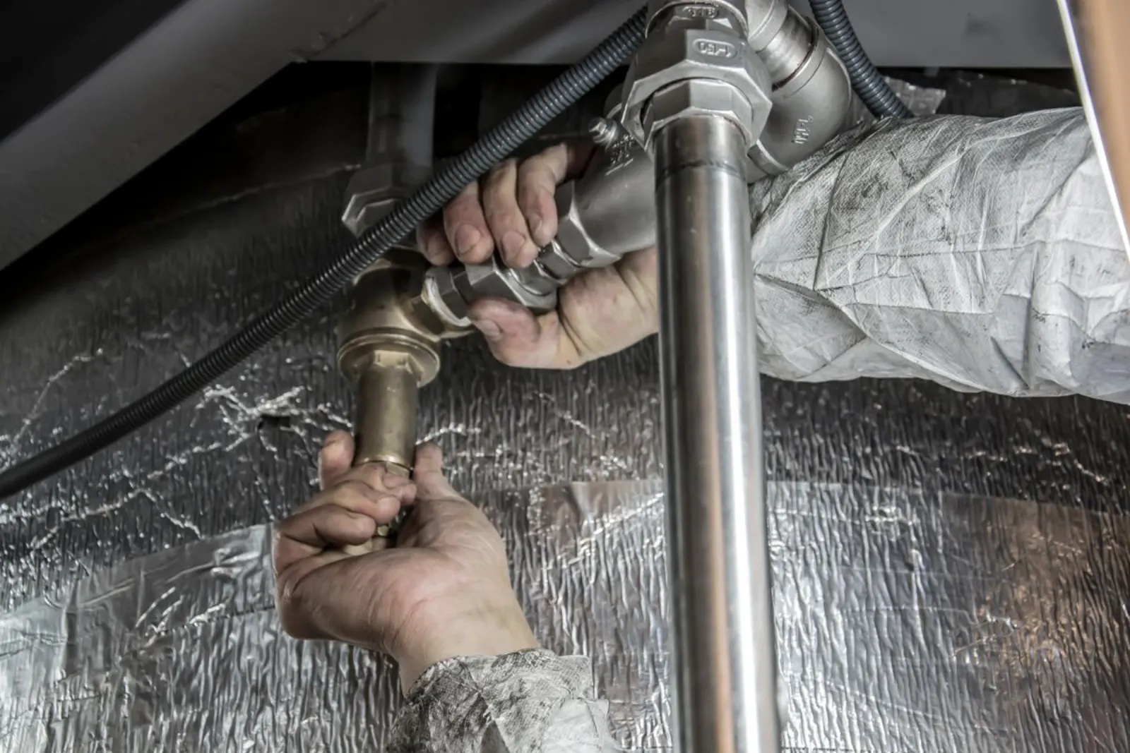 Close-up of a plumber's hands connecting copper pipe fittings