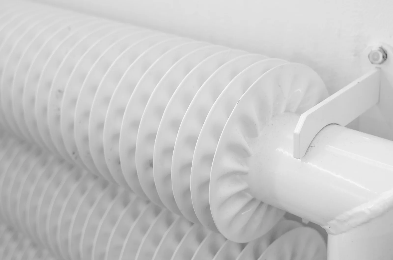 Close-up of white finned radiator tubing, part of a home's hydronic heating system.