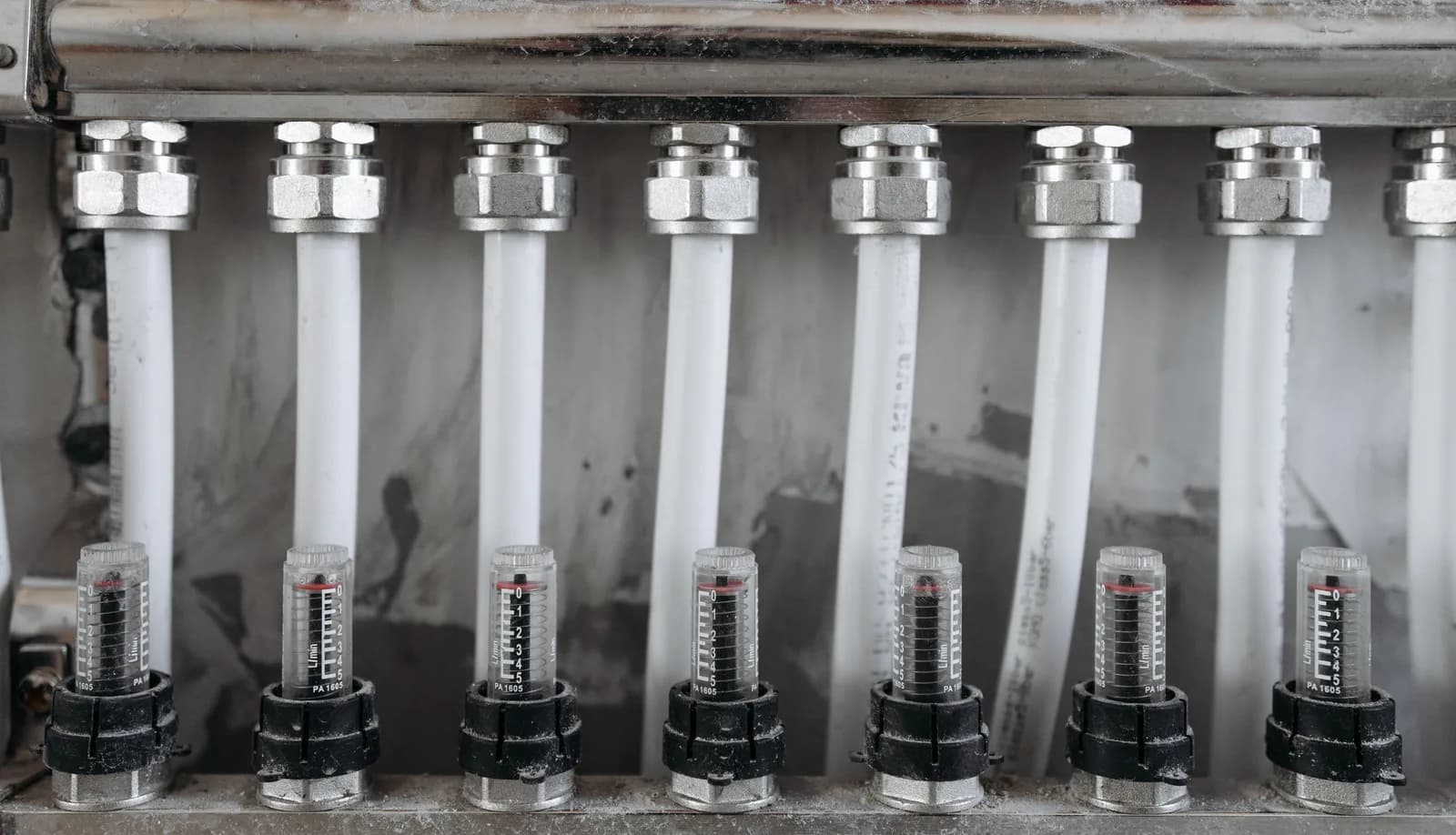 Seven PEX tubing loops feeding into a stainless underfloor-heating manifold, each with its own flow-meter valve.
