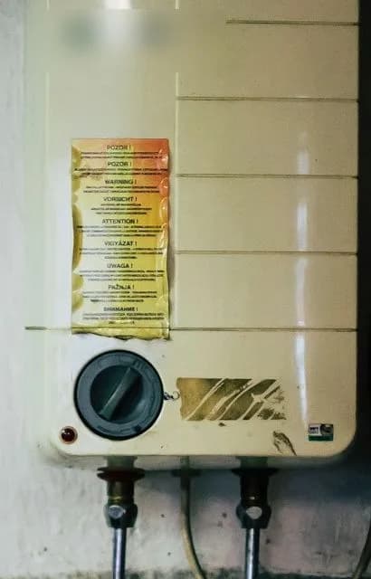 A wall-mounted tankless on-demand water heater unit with its digital control panel, installed in a utility closet.